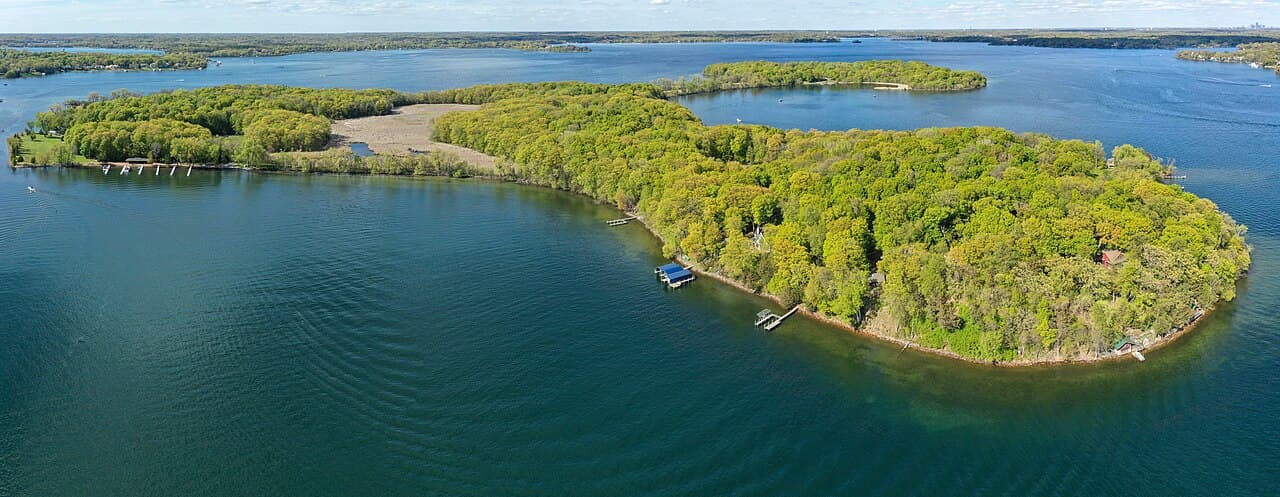 Aerial view of tree-covered Big Island, site of Big Island Nature Park, surrounded by the blue water of Lake Minnetonka